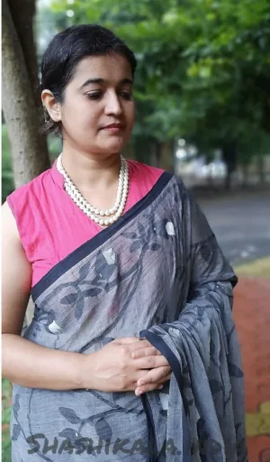 Grey handloom Bengal cotton Jamdani saree with floral woven motifs, worn by woman in elegant traditional style