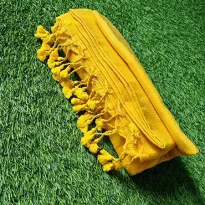 Yellow handloom Bengal cotton saree with soft tassel pallu, folded and displayed on green grass; lightweight traditional Bengal cotton saree.