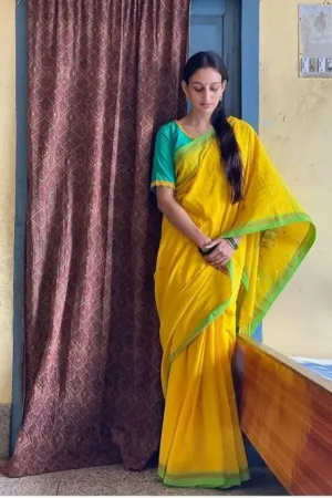 Woman wearing yellow handloom Bengal cotton saree with green border and traditional drape