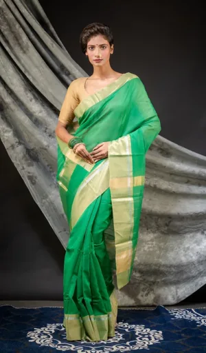 A model wearing a green handloom cotton silk Chanderi saree with a contrasting blouse, styled elegantly against a neutral backdrop.