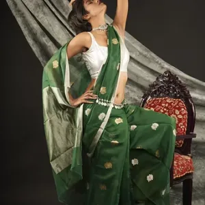Woman wearing a green handloom cotton silk Chanderi saree with golden butti motifs and silver pallu, posing gracefully in a studio setting; elegant festive saree look.