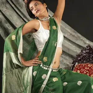 Woman wearing a green handloom cotton silk Chanderi saree with golden butti motifs and silver pallu, posing gracefully in a studio setting; elegant festive saree look.
