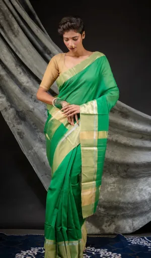 A woman wearing a green handloom cotton silk Chanderi saree with a beige blouse, styled elegantly with traditional accessories.