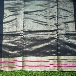 Close view of a Chanderi handloom cotton silk saree featuring a glossy silver pallu with subtle texture work, paired with a cream base and pink striped zari border, displayed on a green grass background.