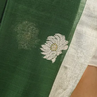 Handloom-Cotton-Silk-Chanderi-4 Close-up of green handloom cotton silk Chanderi saree with silver floral butti motif and soft zari border, showing fine traditional weave detail.