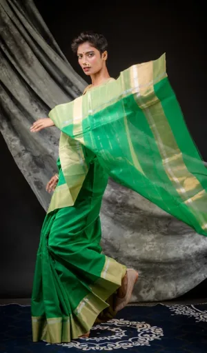 Model wearing a green handloom cotton silk Chanderi saree with gold accents, captured in a dynamic pose against a neutral background.