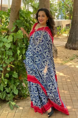 Woman wearing blue handloom double ikat cotton saree with white geometric patterns and red border