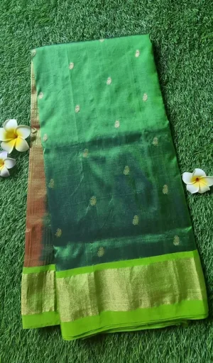 Green handloom Chanderi Paithani saree with gold motifs and a contrasting border, neatly folded on a textured surface.