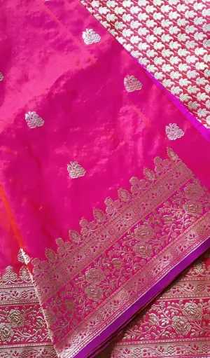 Handloom Katan Silk Sona Roopa Banarasi saree in vibrant pink with elegant gold zari floral and paisley motifs. The saree is finished with a rich gold zari border featuring intricate floral designs, creating a luxurious and traditional look.