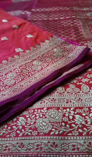 Handloom Katan Silk Sona Roopa Banarasi saree in rich maroon with intricate silver zari floral patterns and paisley motifs. The saree features a stunning border with detailed floral designs in silver, creating an elegant and luxurious traditional look.