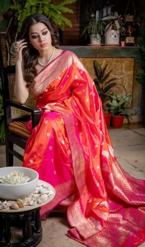 Elegant woman draped in a Handloom Katan Silk Sona Roopa Banarasi saree with intricate gold zari work, featuring a vibrant pink color with floral and heart motifs. The saree is finished with a golden border, exuding traditional luxury and grace.