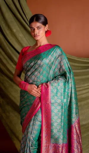Teal green handloom Katan silk Tanchoi Banarasi saree with intricate all-over floral weaving and deep pink zari border