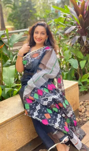 Black handloom pure cotton Jamdani saree with multicolour geometric floral motifs, worn by woman in outdoor setting