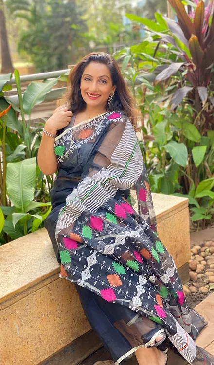Handloom-Pure-Cotton-Jamdani-3 Black handloom pure cotton Jamdani saree with multicolour geometric floral motifs, worn by woman in outdoor setting