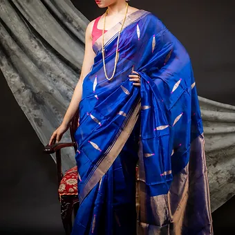 Handloom-Pure-Silk-Chanderi-1 Woman wearing a royal blue pure silk Chanderi handloom saree with silver butti motifs and zari border, posing in a studio setting; elegant festive silk saree look.