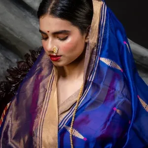Woman wearing a royal blue pure silk Chanderi handloom saree with gold zari border and butti motifs, styled in a close-up traditional portrait; elegant festive silk saree look.