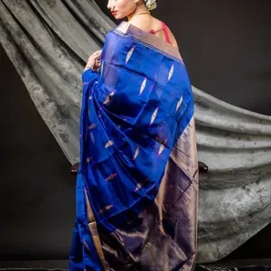 Woman wearing a royal blue pure silk Chanderi handloom saree with silver zari motifs and border, posing against a draped backdrop; elegant festive silk saree style.