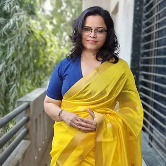Handloom-Pure-Silk-Chanderi-4 Woman wearing a yellow saree with a blue blouse, standing confidently with a slight smile.