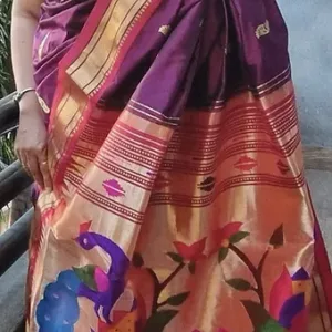 Handloom pure silk Paithani saree with intricate peacock and floral designs in vibrant colors, draped elegantly.