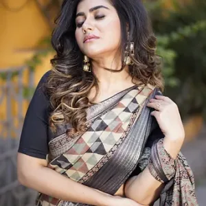 Woman draped in a handloom Tussar silk Mangalgiri saree featuring Ajrakh-inspired geometric triangle patterns in earthy beige, black and maroon, paired with a rich black textured zari border and styled with ethnic earrings.