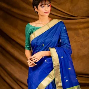 Woman wearing a royal blue handloom cotton silk Maheshwari saree with gold zari border and small butti motifs, posing in a studio setting; elegant festive Maheshwari saree look.