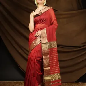 Woman wearing a maroon handloom cotton silk Maheshwari saree with gold zari border and striped pallu, posing in a traditional setup; elegant festive Maheshwari saree style.
