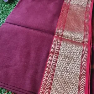 Maroon handloom cotton silk Maheshwari saree with intricate gold zari border, displayed flat on green grass; elegant traditional Maheshwari cotton silk saree.