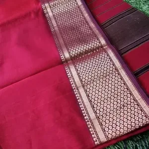 Maroon handloom cotton silk Maheshwari saree with intricate gold zari border and striped pallu, displayed on green grass; elegant traditional Maheshwari saree.