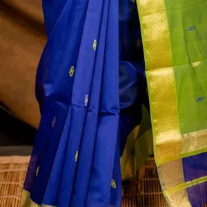 Royal blue handloom cotton silk Maheshwari saree with small butti motifs and contrasting green zari border, shown in close-up; elegant traditional Maheshwari saree design.