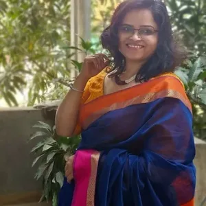 Model wearing a handloom cotton silk Maheshwari saree in deep navy blue with an orange and pink resham border, styled for an elegant traditional look