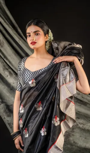 Model wearing a black handloom silk Chanderi saree with floral embroidery and a contrasting blouse, styled elegantly with accessories.