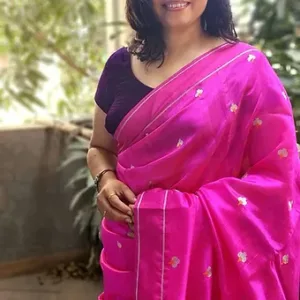 Woman wearing a bright pink handloom silk Chanderi saree with floral embroidery, showcasing intricate details and vibrant color.