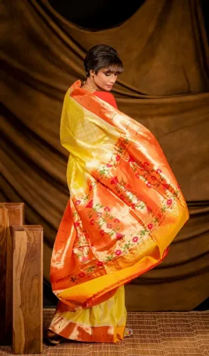 Yellow and orange handloom pure silk Paithani brocade saree with floral zari weaving, worn by woman in traditional style