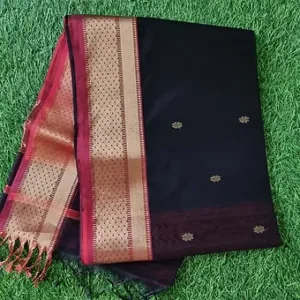 Black handloom pure silk Chanderi saree with maroon and gold zari border and small butti motifs, neatly folded on green grass; elegant traditional silk saree.