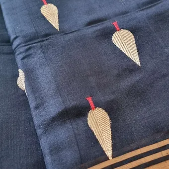 Handloom-pure-silk-chanderi-2 Navy blue handloom pure silk Chanderi saree with woven leaf butti motifs and subtle zari border, shown in close-up; elegant traditional silk saree fabric.