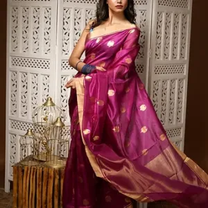 Woman wearing a magenta pure silk Chanderi handloom saree with golden butti motifs and zari border, posing in a traditional indoor setting; elegant festive silk saree style.