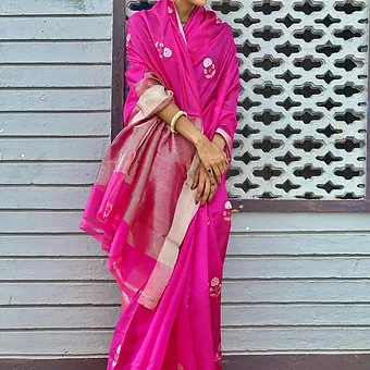 Pink Pure Silk Chanderi Saree with Floral Butta & Silver Zari Pallu Woman wearing a bright pink pure silk Chanderi saree featuring delicate white floral butta motifs and a silver zari pallu with border highlights, styled with minimal jewelry.
