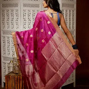 Woman wearing a magenta pure silk Chanderi handloom saree with golden butti motifs and rich zari pallu, posing in an indoor traditional setting; elegant festive silk saree look.
