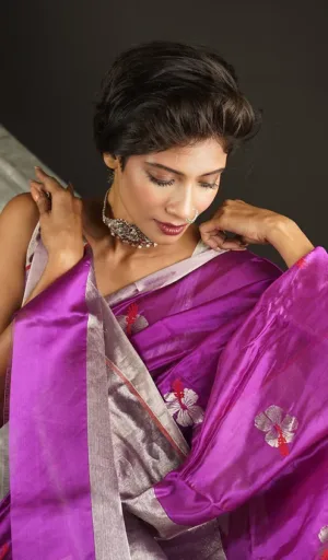 A woman wearing a handloom pure silk Chanderi saree in shades of purple with floral embroidery, styled elegantly with accessories.