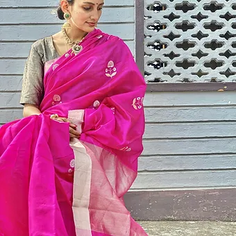 Magenta Pure Silk Chanderi Saree with White Floral Butta & Silver Zari Border Model wearing a magenta pure silk Chanderi saree featuring delicate white floral butta motifs and a soft silver zari border, paired with a contrasting blouse and traditional jewelry