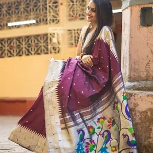 A woman wearing a handloom pure silk Paithani saree with intricate floral and peacock designs in vibrant colors.