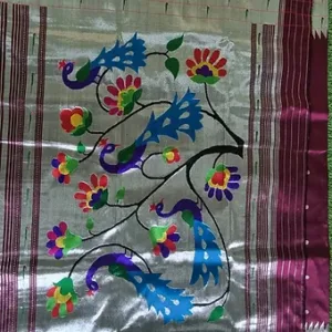 Handloom pure silk fabric with intricate floral and peacock motifs in vibrant colors on a silver background.