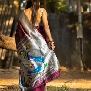 A woman wearing a traditional saree with intricate peacock designs in vibrant colors, draped elegantly over her shoulder.