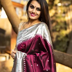 Woman wearing a traditional saree with a maroon and silver design, featuring intricate patterns and embellishments.