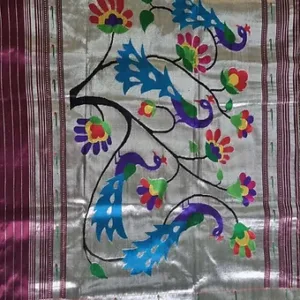 Handloom pure silk triple Muniya Paithani with intricate floral and peacock motifs in vibrant colors on a silver background.