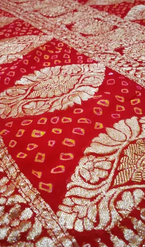 Close-up of Handwoven Pure Chiffon Banarasi saree in red with intricate gold zari floral patterns and delicate diamond-shaped motifs in gold and pink, showcasing the traditional craftsmanship and elegant design