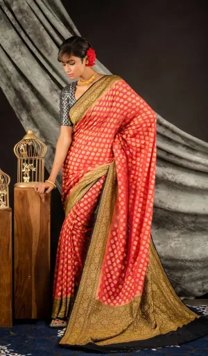 Handwoven pure georgette Banarasi saree in red with gold motifs and a contrasting border, worn by a model with a floral accessory in her hair.