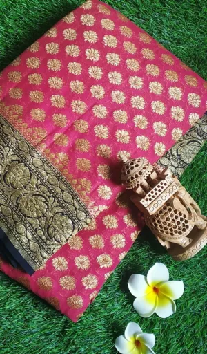 Handwoven pure georgette Banarasi saree with intricate gold patterns on a pink background, accompanied by a decorative wooden piece.