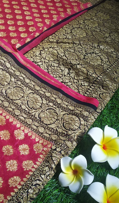 Handwoven-Pure-Georgette-Banarasi-Saree-5 Handwoven pure georgette Banarasi saree with intricate gold patterns and a contrasting red border, displayed with decorative flowers.