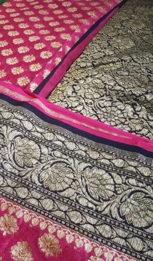 Handwoven pure georgette Banarasi saree featuring intricate gold floral patterns on a black background with a contrasting pink border.